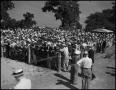 Photograph: [Large crowd of people standing behind a fence]