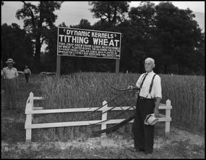 Primary view of object titled '[Man standing in front of a small plot of wheat, holding a scythe]'.