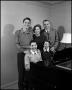 Photograph: [Family standing at their piano]