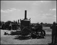 Photograph: [Man sitting on a wheel of an engine]