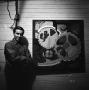 Photograph: [A man standing next to a painting]