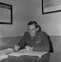 Photograph: [John Spencer Church in uniform sitting at a desk]