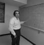 Photograph: [Man standing in front of a blackboard]
