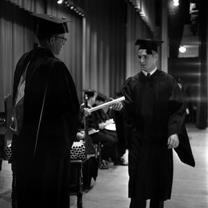 Primary view of object titled '[Faculty handing diploma to student on stage]'.
