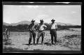 Photograph: [Three men standing and posing in a desert]