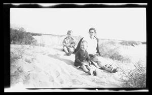 Primary view of object titled '[Irene, Byrd III, and John Williams sitting in the sand]'.