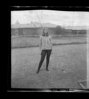 Primary view of object titled '[Diane in tights standing in a backyard]'.