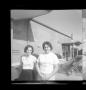 Photograph: [Two women sitting on a car in front of a barber shop]