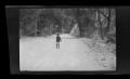 Photograph: [A small child standing on a road in the woods]