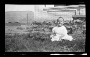 Primary view of object titled '[Photo of baby Charles sitting in front of a house]'.