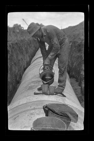 Primary view of object titled '[A man standing on an underground pipe]'.