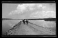 Photograph: [Three men and a mule walking next to a lake]