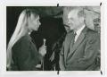 Photograph: [Woman Holding Microphone and Speaking with Man]