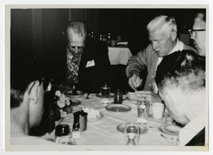Primary view of object titled '[Men Sitting at a Table Having Dinner]'.