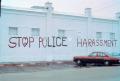 Photograph: [Brick wall with graffiti: "Stop police harrassment"]
