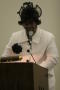 Photograph: [Woman in white business suit speaking into microphone]