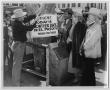 Photograph: [Photograph of Sam Myres, two men and a woman hanging up a sign]