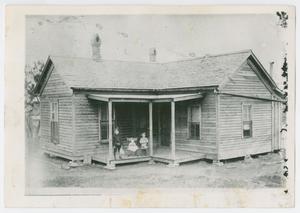 Primary view of object titled '[Photograph of three children on the porch of a wooden house]'.