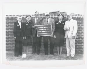 [Group Holding Plaque in Front of Wall]