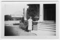 Photograph: [Unidentified Woman standing in front of a house]