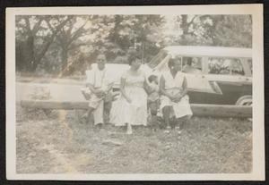 Family seated in front of stationwagon
