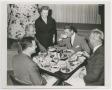 Primary view of [Photograph of Helen Corbitt with men at Christmas dinner]