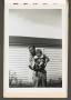 Photograph: [Man with Cigar Holding Child in Front of Home]