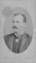 Photograph: [Portrait of a man with a mustache wearing a dark three piece suit]