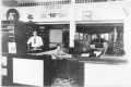 Primary view of [Interior of a car company, possibly Kiefner Motor Co., people behind a desk]