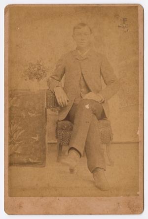 [Unknown Man Sitting With Legs Crossed on Fabric Chair]