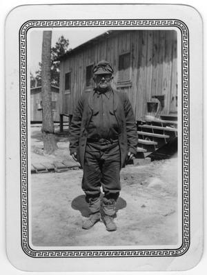 Primary view of object titled '[ Man stands outside CCC camp buildings]'.