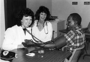 [Nursing students Susan Whiteneck and Beth Kohlmeyer check blood pressure of Houston Lewis.]