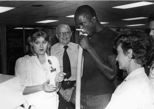 Janice Barham, left, checks lung capacity of Lee basketball player Steve Morris during Great American Smoke-out.  Mrs. Barham and Brenda Braser (right) are members of the Humana Hospital respiratory team, looking on is Jack Cantrell, a respiratory team volunteer helper.