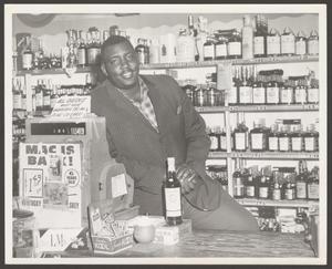 [Smiling Man Behind Liquor Store Counter]