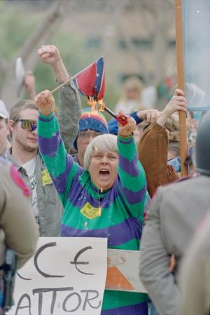 Primary view of object titled '[KKK Rally Protester Burning a Confederate Flag]'.