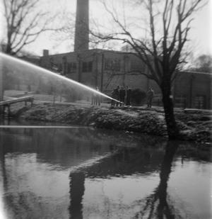 Primary view of object titled '[Men Standing Around Hose Spraying Over Lake]'.