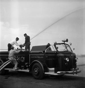 Primary view of object titled '[Three Men Spraying Fire Hose on Baton Rouge Fire Department Truck]'.