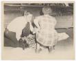 Photograph: [Two People Crouched Next to Supine Woman]