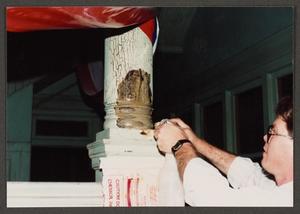 [Person Removing Paint Analysis Sheet from Stairway Post #2]