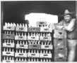 Photograph: [J. T. Brewer leaning on a stack of wooden boxes]