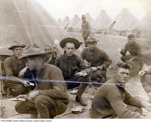 [Group of World War I Army enlisted men eating beside tent rows]