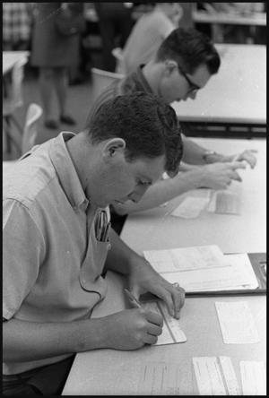 [Two Young Men Filling Out Registration Forms at M.U.]