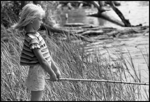 [Young Girl Fishes Next to the Water's Edge]