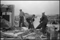 Photograph: [Men Carry Out Washing Machine From Rubble]
