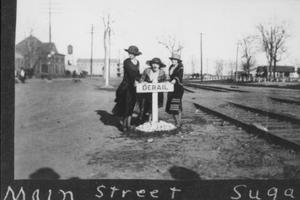 [Photograph of three Sugar Land teachers standing in front of a railroad sign]