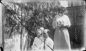 [Man, Woman, and Child Posing by a Bush]