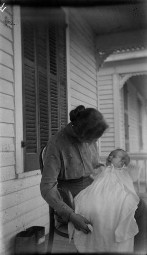[Woman Sitting and Holding an Infant on a Porch #1]