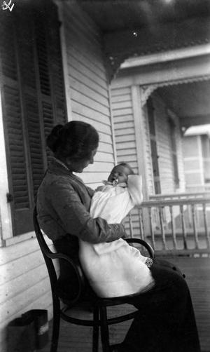 [Woman Sitting and Holding an Infant on a Porch #2]