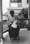 Photograph: [Woman Holding an Infant on a Porch #1]
