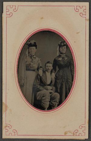 [Photograph of A Seated Man and Two Women]